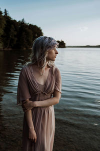 Young woman standing by lake