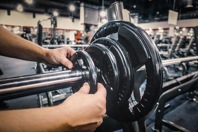 Close-up of man putting weights in barbell at gym