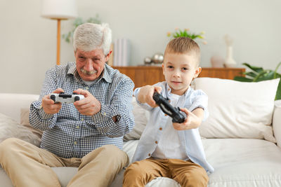 Portrait of boy using mobile phone while sitting on sofa at home