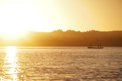 Silhouette boat sailing in sea against clear sky during sunset