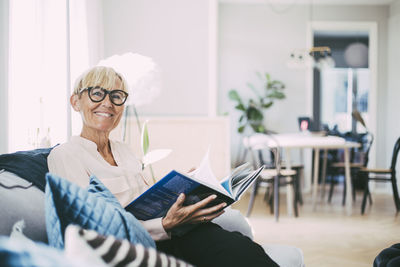 Portrait of woman sitting in sofa at home reading book