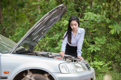 Businesswoman looking at car engine