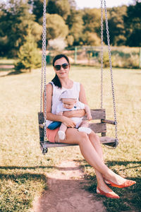 Young woman sitting on swing at playground