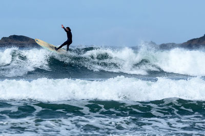 Man surfing in sea against sky