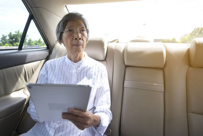 Senior woman using digital tablet sitting in car