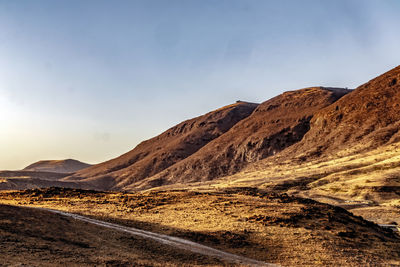 Scenic view of road by mountains against sky