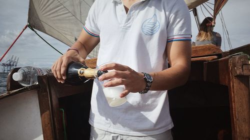 Midsection of man holding ice cream at sea shore