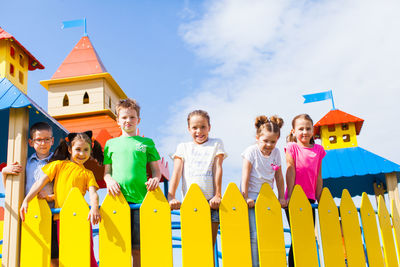 Portrait of cute kids at playground against sky