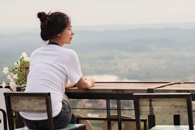 Young woman sitting on table against mountain