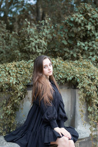 Beautiful young woman sitting by plants