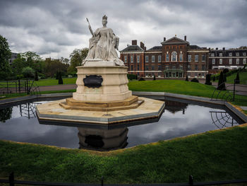 Statue in park against cloudy sky