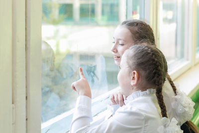 Happy girl looking away while standing by window