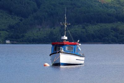 Boat moored in sea against mountain