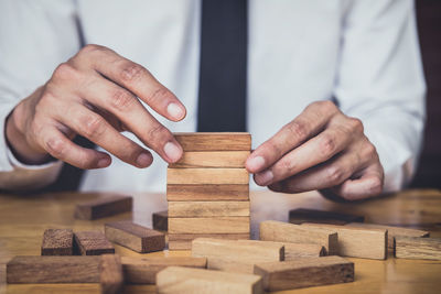 Midsection of businessman stacking wooden toy blocks at desk