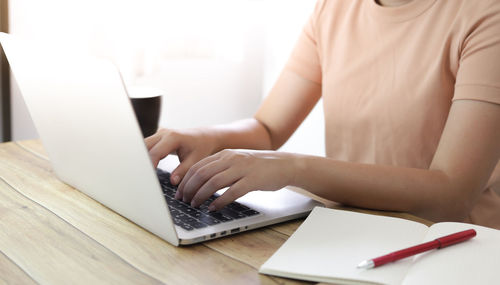 Midsection of woman using smart phone on table