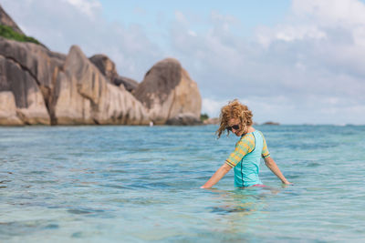 Smiling woman standing in sea against sky