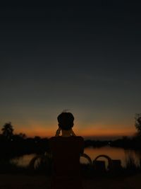 Rear view of silhouette man standing against clear sky during sunset