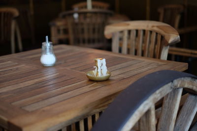 Candlestick holder by salt on wooden table at cafe