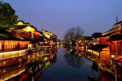 Canal amidst illuminated buildings against sky at night