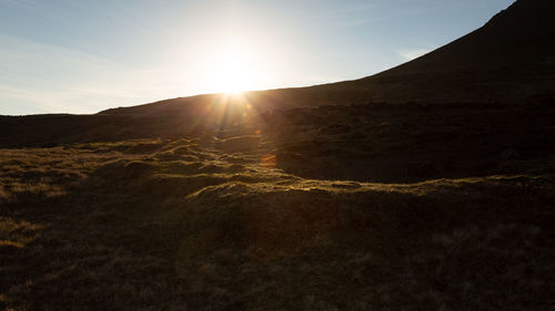 Scenic view of sun shining over mountain