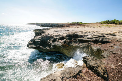 Scenic view of rocks in sea against sky
