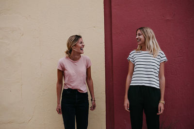 Cheerful friends standing against wall