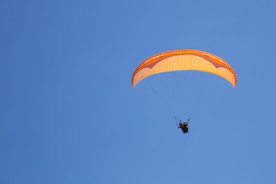 Low angle view of person paragliding against clear blue sky