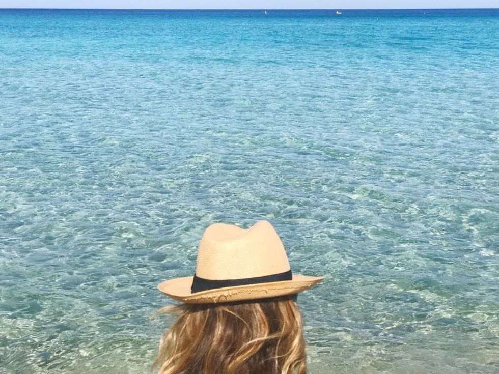 REAR VIEW OF WOMAN IN HAT ON SEA