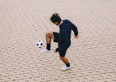 Sportsman kicking soccer ball with knee