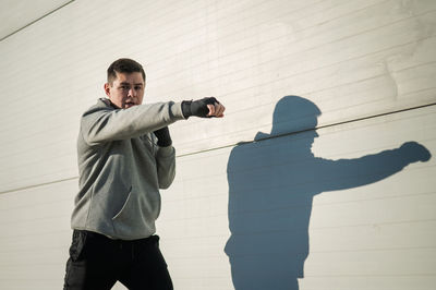 Side view of man standing against wall