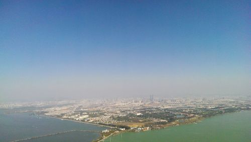 Aerial view of city by sea against clear blue sky