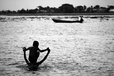 Rear view of silhouette man in sea against sky