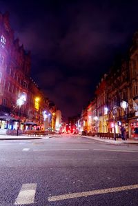 Illuminated city street against sky at night