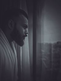 Portrait of young man looking through window