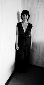 Portrait of woman standing against wall at home