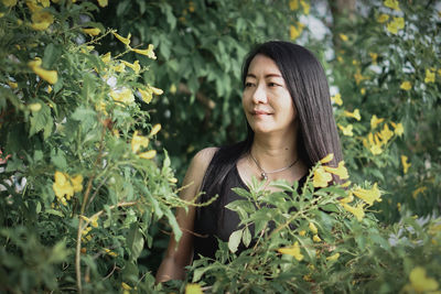 Young woman standing against plants