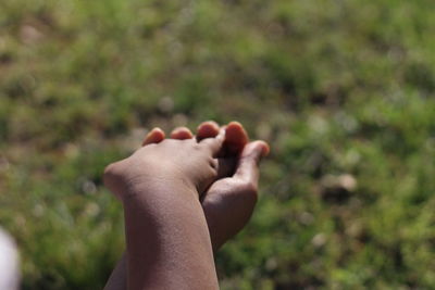 Cropped hand holding baby on sunny day