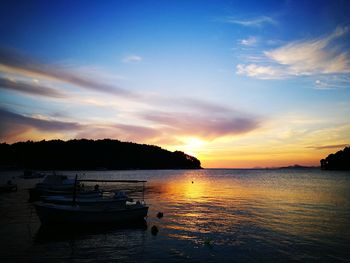 Boats moored on sea against sky during sunset