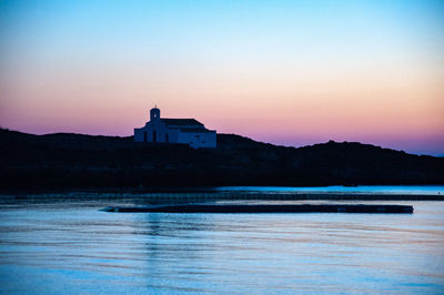 Building by sea against clear sky during sunset