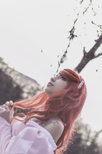 Low angle view of young woman against clear sky