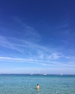 Rear view of woman standing in sea against sky