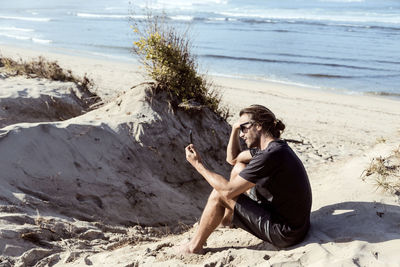 Man using smartphone on beach