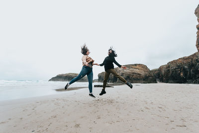 Full length of woman standing on beach against clear sky