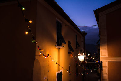 Illuminated street light against building in the narrow street at night