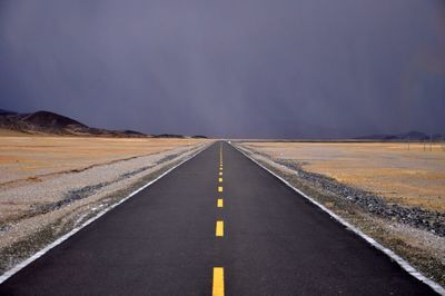 Empty road amidst landscape against sky