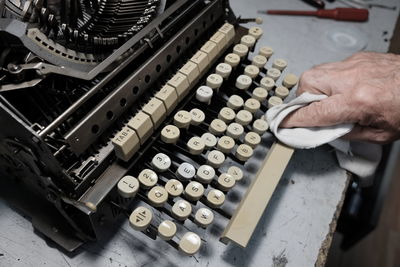 Cropped image of man cleaning typewriter on table