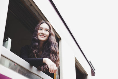 Portrait of smiling young woman against sky