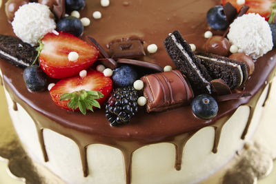 Cake decorated with strawberry and chocolate on yellow background