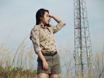 Young woman looking away while standing on field