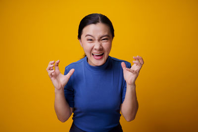 Portrait of woman standing against yellow background